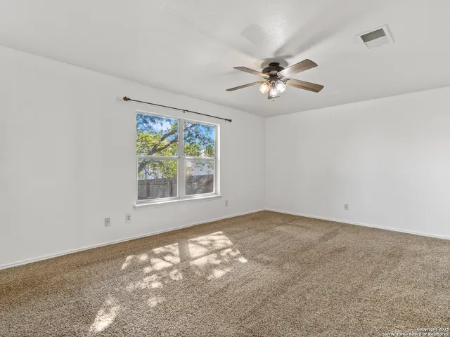 an empty room with windows and fan