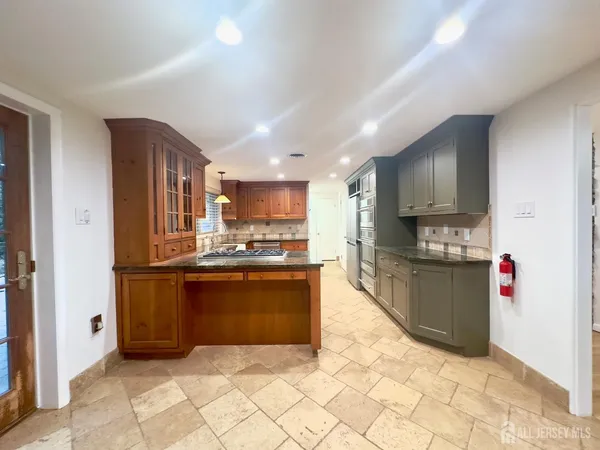 a large kitchen with stainless steel appliances kitchen island granite countertop a refrigerator and a sink