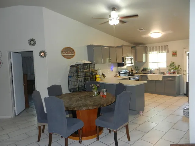 a kitchen with a dining table chairs and refrigerator