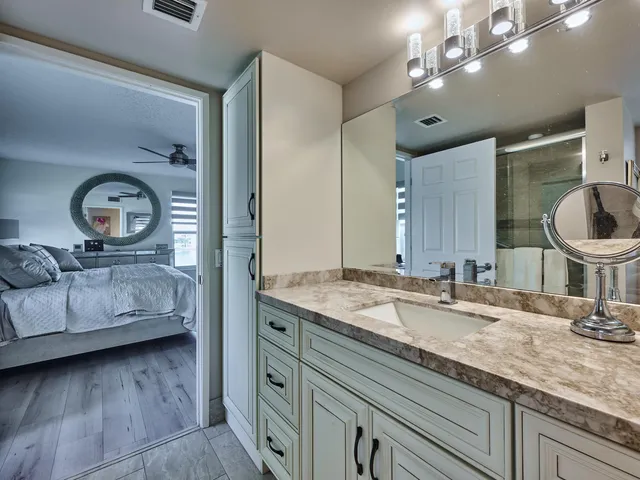 a en suite bathroom with a granite countertop sink and a mirror