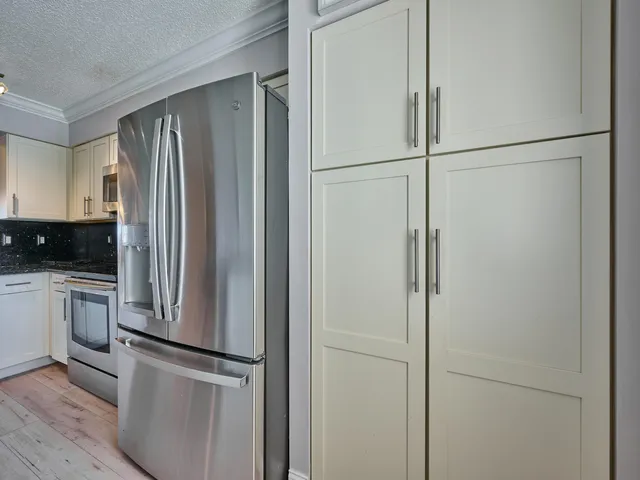 a view of a refrigerator in kitchen and white cabinets