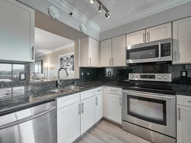 a kitchen with stainless steel appliances granite countertop a sink a stove a microwave oven and a granite counter tops with wooden floors