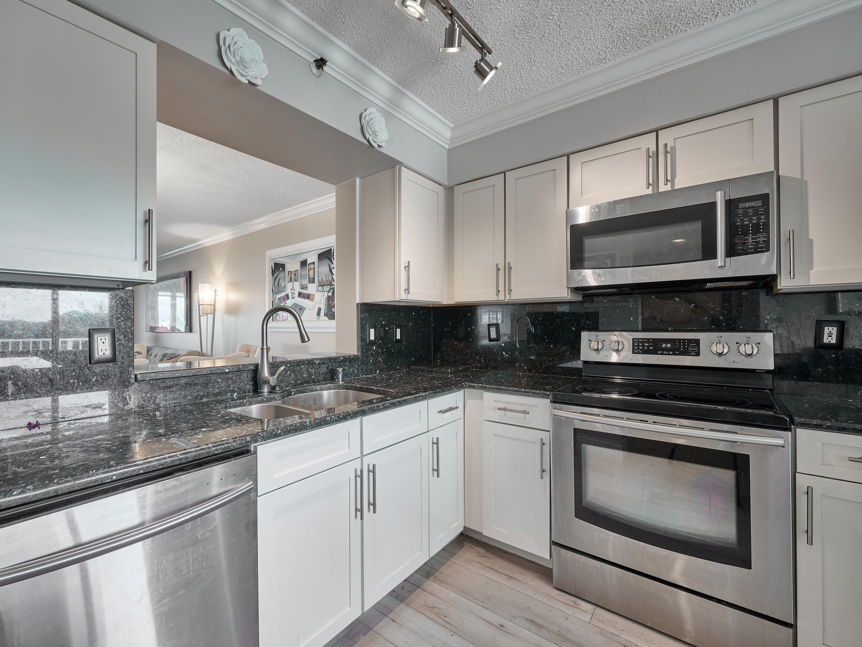 14112 Huntington Pointe Drive, Unit 401 Delray Beach, FL 33484 - Photo 10 of 49 a kitchen with stainless steel appliances granite countertop a sink a stove a microwave oven and a granite counter tops with wooden floors