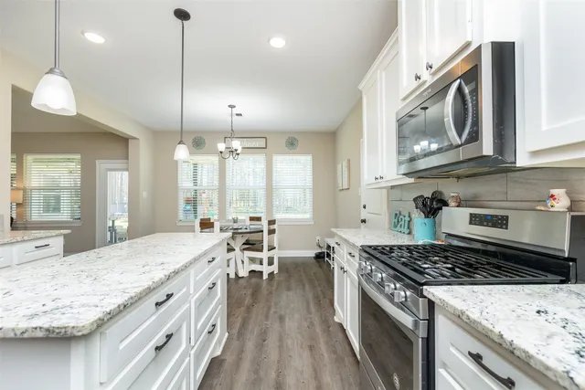 a kitchen with stainless steel appliances granite countertop a stove and a wooden floors