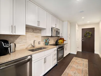a kitchen with a sink dishwasher a stove and white cabinets