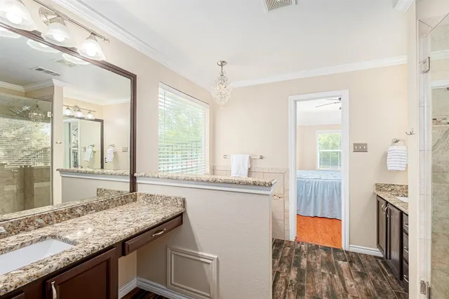 a en suite bathroom with a granite countertop shower a sink and a mirror