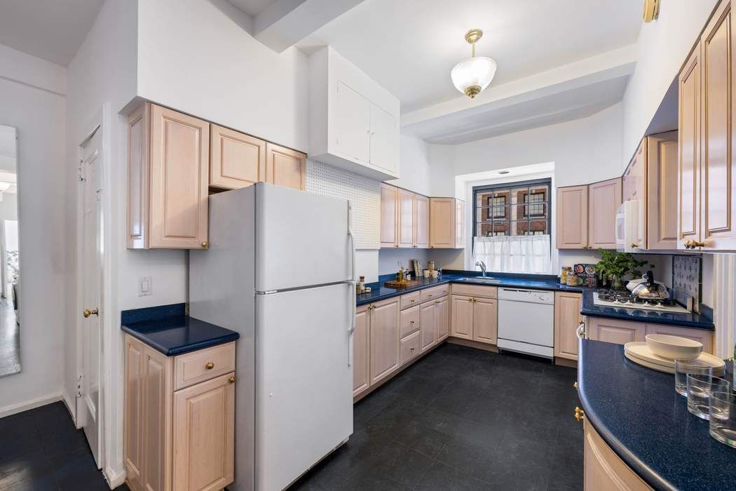 129 East 69th Street, Unit 2/3A Manhattan, NY 10021 - Photo 4 of 12 a kitchen with a refrigerator a stove a sink cabinets and a dining table
