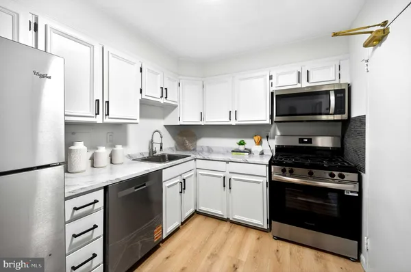 a kitchen with stainless steel appliances granite countertop a stove top oven a sink dishwasher and a refrigerator with wooden cabinets