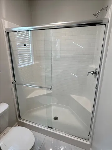 a bathroom with a shower a sink a toilet and mirror