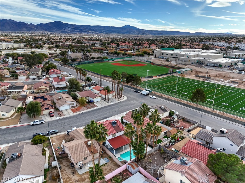 581 Carleton Drive Henderson, NV 89014 - Photo 34 of 37 An aerial perspective reveals a vibrant neighborhood with residential properties, athletic fields, and distant mountains.