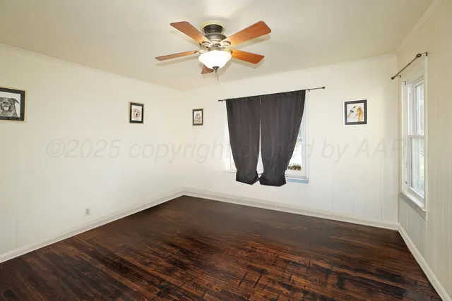 a view of an empty room with wooden floor and a ceiling fan