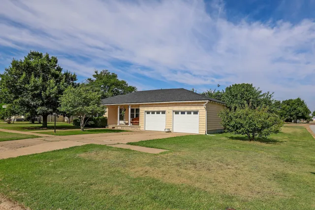 a front view of a house with a yard and trees