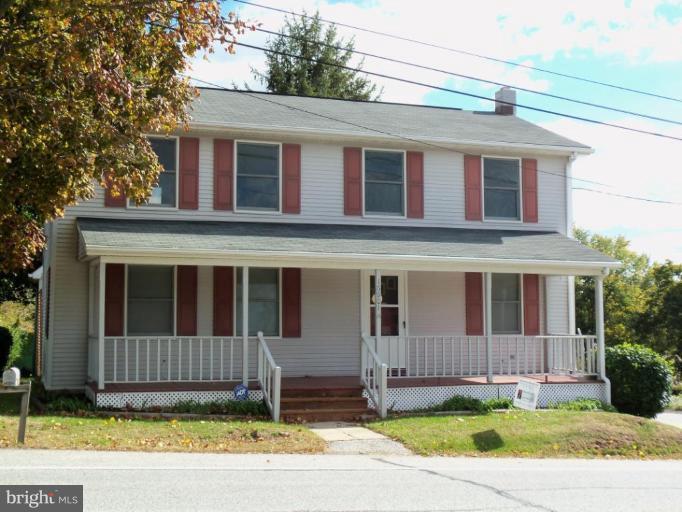 a view of a house with a yard and a large tree front of house