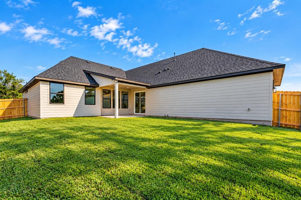 1632 West Wintergreen Road Lancaster, TX 75134 - Photo 27 of 30 Expansive backyard featuring a manicured lawn, wood fencing, and a covered patio area