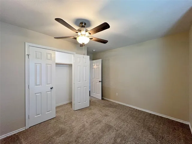 an empty room with closet and a ceiling fan