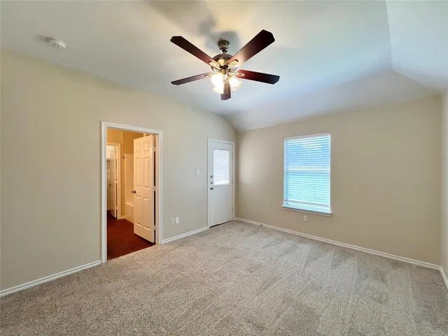 a view of an empty room with window and ceiling fan