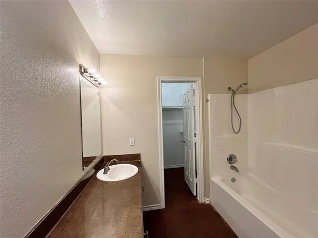 a bathroom with a tub shower vanity and a sink