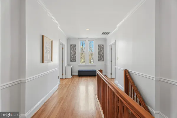 a view of a hallway with wooden floor and staircase