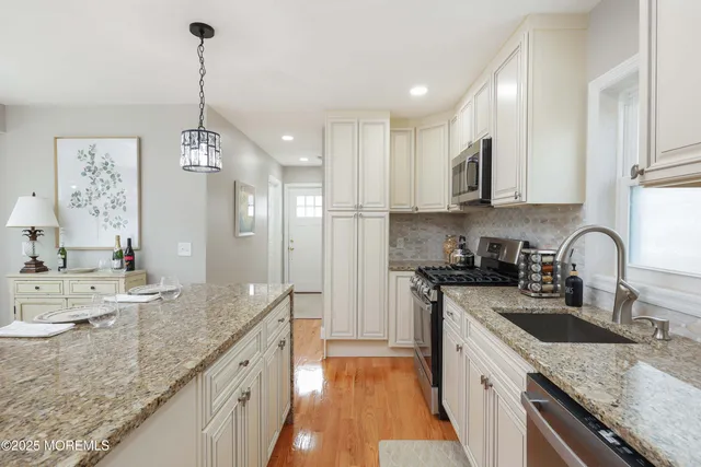 a kitchen with stainless steel appliances granite countertop a refrigerator a stove a sink a dining table and chairs