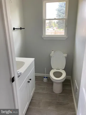 a bathroom with a toilet a sink a window and mirror