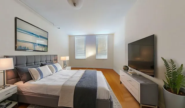 a bedroom with bed tv and window