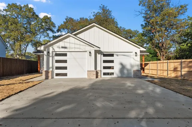 a view of a white house with a large space and large trees