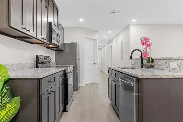 a kitchen with granite countertop stainless steel appliances a sink stove top oven and cabinets