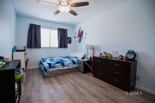 199 East Upjohn Avenue Ridgecrest, CA 93555 - Photo 15 of 30 a bedroom with a bed and wooden floor