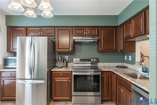 a kitchen with stainless steel appliances granite countertop a refrigerator sink and stove