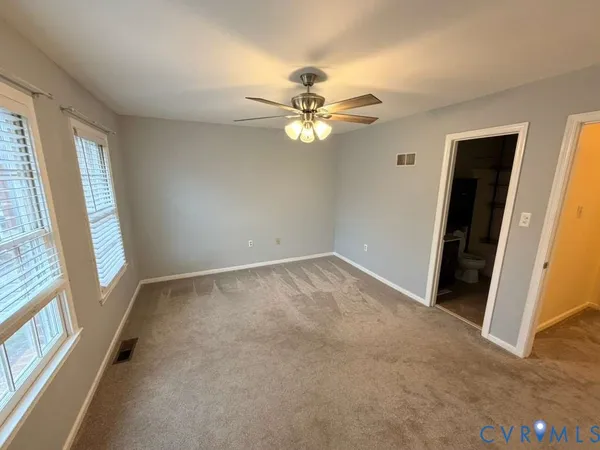 an empty room with windows and fan