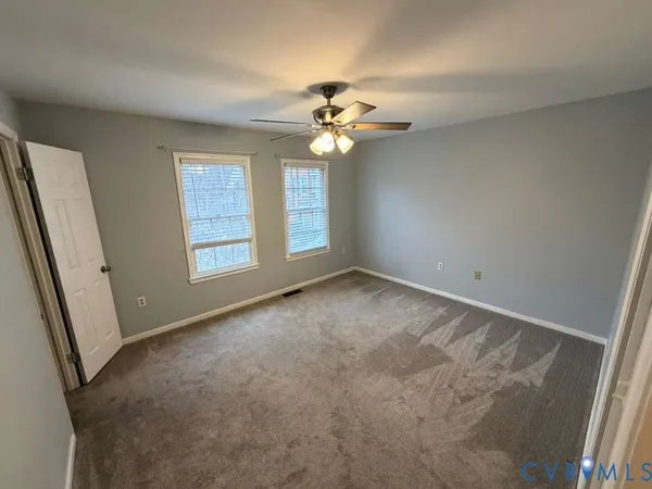 an empty room with windows and fan