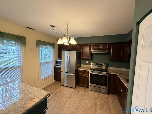 a kitchen with granite countertop stainless steel appliances and wooden floor