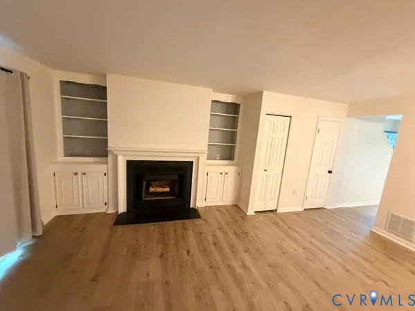 a view of empty room with wooden floor and fireplace