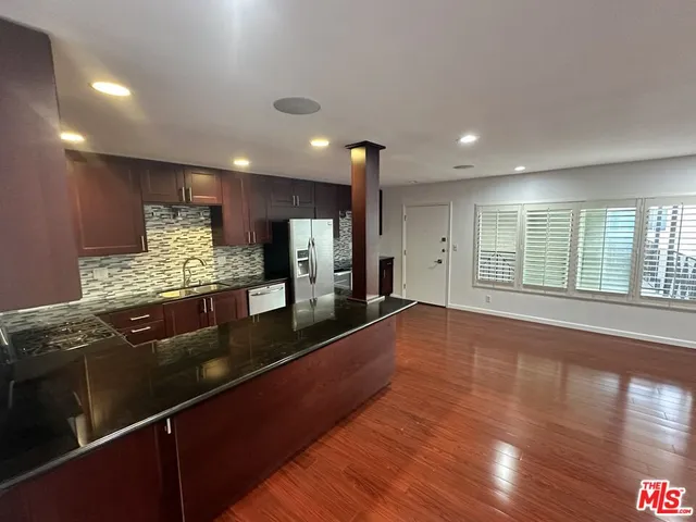 a large kitchen with stainless steel appliances granite countertop a large counter top and a wooden floors