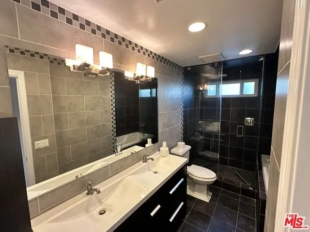 a bathroom with a double vanity sink toilet and shower