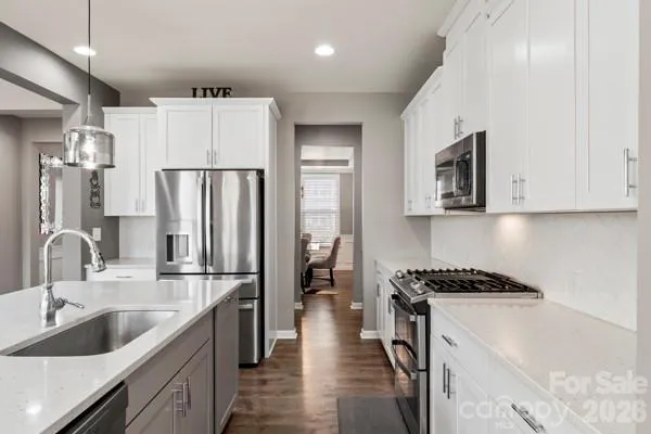 a kitchen that has a refrigerator a sink and white cabinets