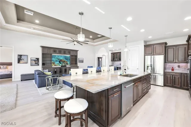 a large kitchen with stainless steel appliances a sink dishwasher a stove a refrigerator with island and chairs