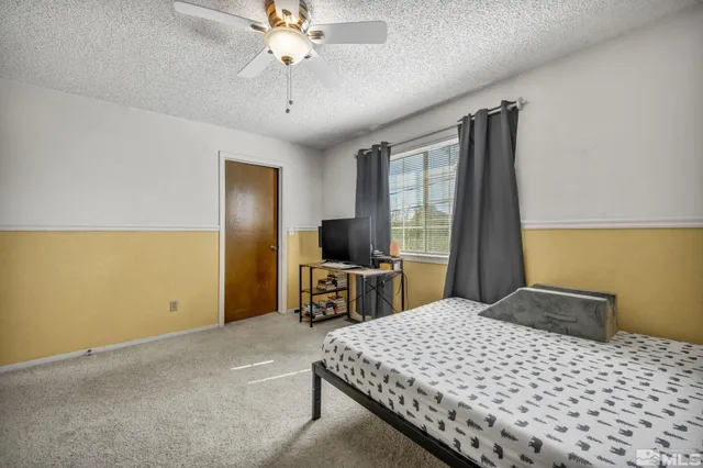 a bedroom with a large bed and a flat tv screen on dresser