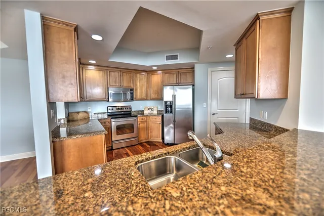 a kitchen with granite countertop a refrigerator sink and stove