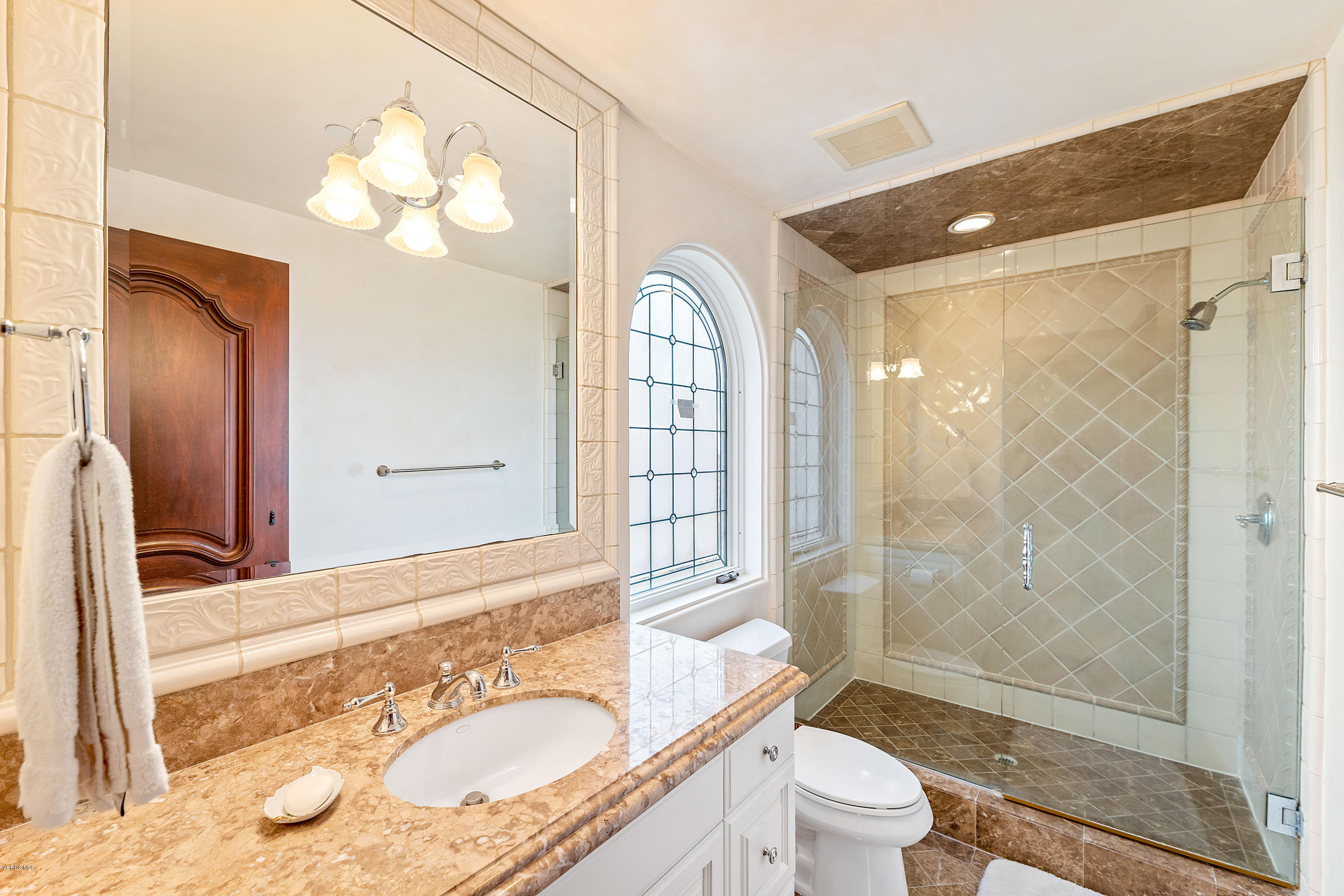 a bathroom with a granite countertop sink toilet a mirror and shower