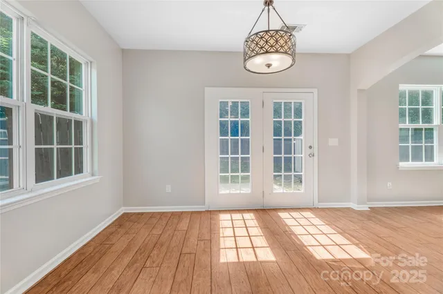 an empty room with wooden floor cabinet and windows
