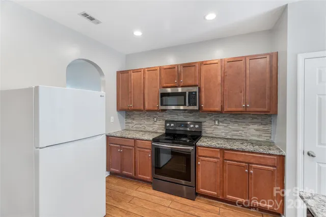 a kitchen with stainless steel appliances granite countertop a stove a refrigerator and a microwave