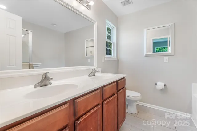 a bathroom with a granite countertop sink a toilet and a mirror