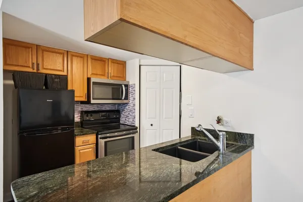 a kitchen with granite countertop a refrigerator a stove and a sink