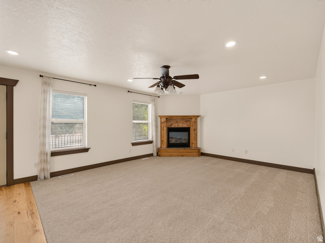 1279 West 1500th Street North Mapleton, UT 84664 - Photo 30 of 83 Spacious room featuring a corner-set fireplace with a wood mantel, overhead ceiling fan with light fixture, recessed lighting, and dual windows