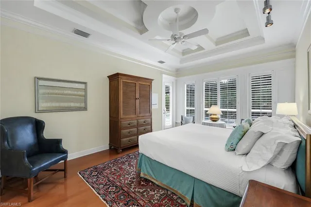 a bedroom with a large bed a chandelier and dresser
