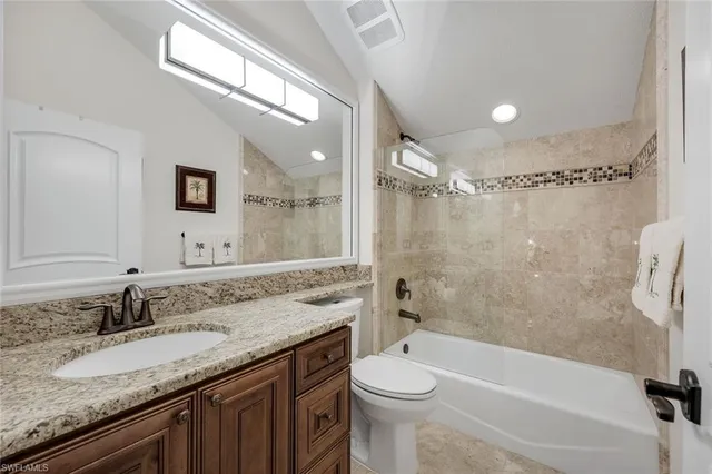 a bathroom with a granite countertop sink a mirror a bathtub and toilet