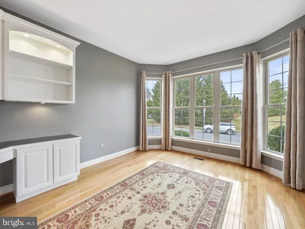 a view of an empty room with wooden floor fireplace and a window