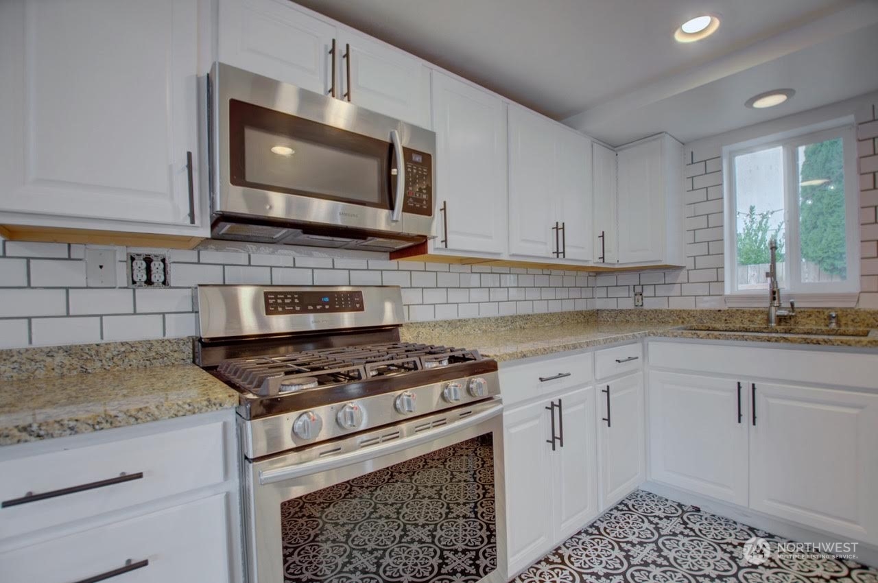 1321 Golf Club Road Southeast Lacey, WA 98503 - Photo 10 of 25 a kitchen with granite countertop a stove a sink and a microwave