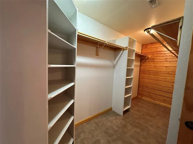 a view of walk in closet with empty racks